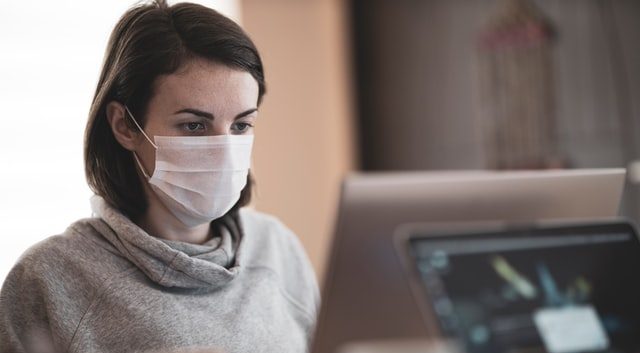 woman with mask at a computer